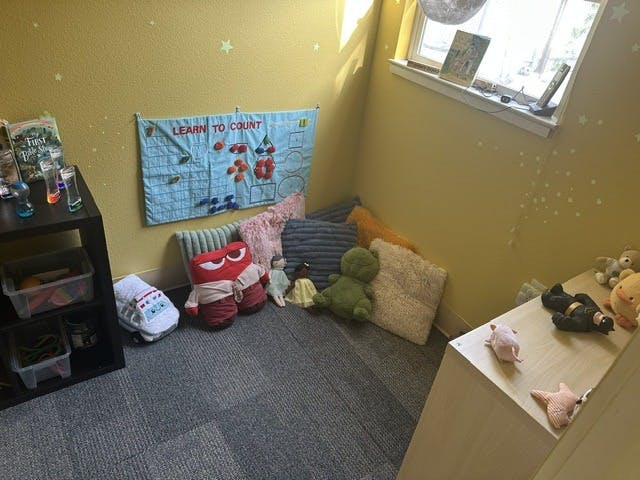 Childs reading corner with cushions, plush toys, and a counting wall chart