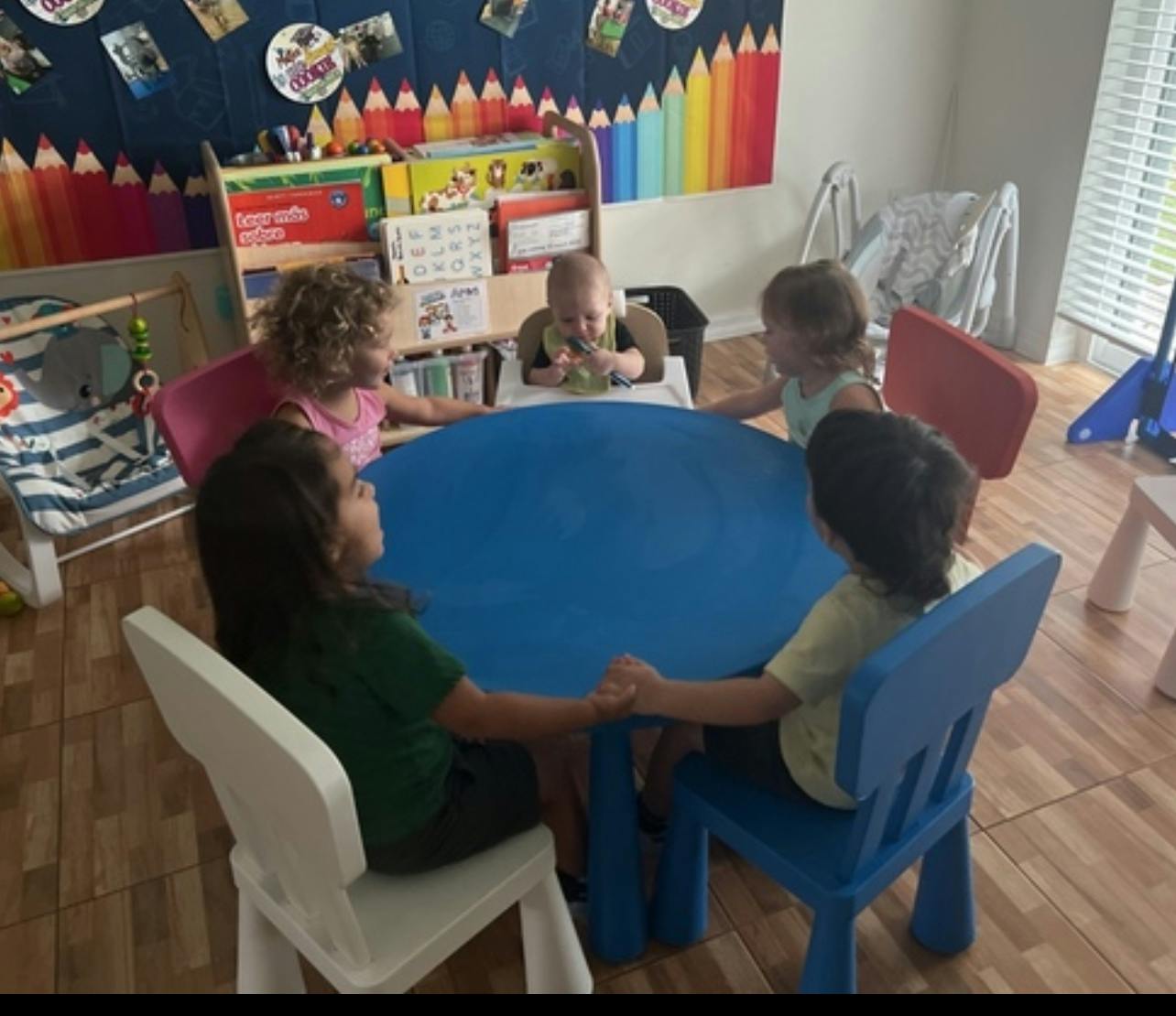 Children and a baby sitting around a blue table