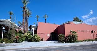 Red building with palm trees and a clear blue sky