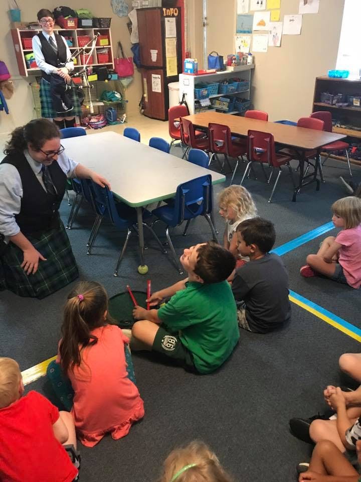 Adult kneeling with children sitting on floor in classroom