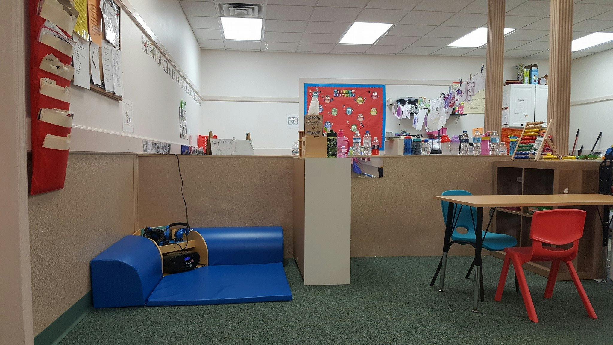 Classroom with blue mat, small table, and chairs