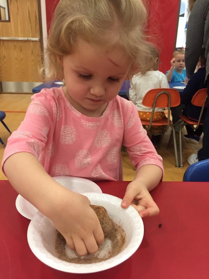 Child with hands in a bowl of brown and white powder