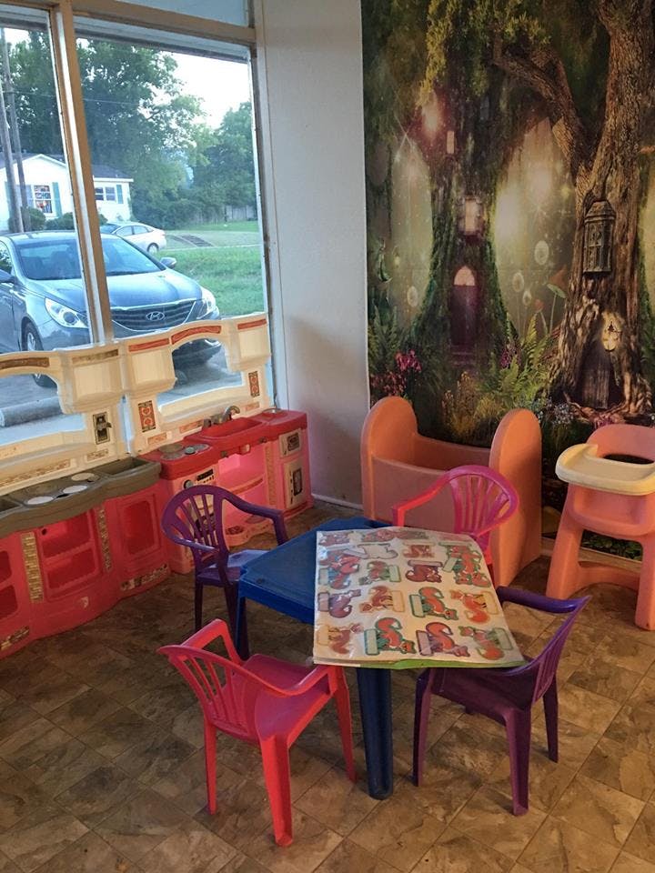 Children's play area with small table and chairs, play kitchen, and mural