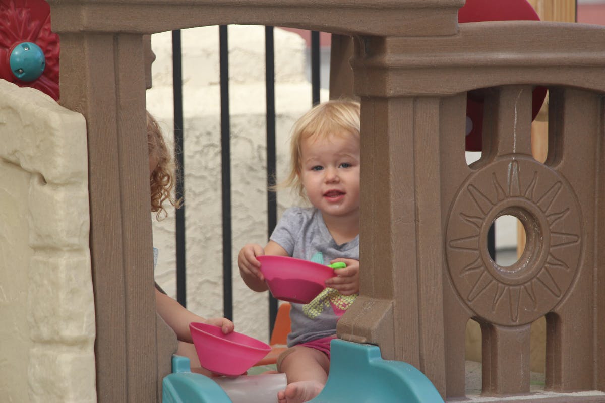 Child playing with pink scoops on a playground structure