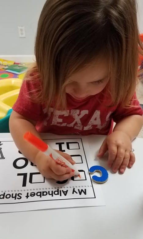 Child marking a checkbox on a worksheet with a marker