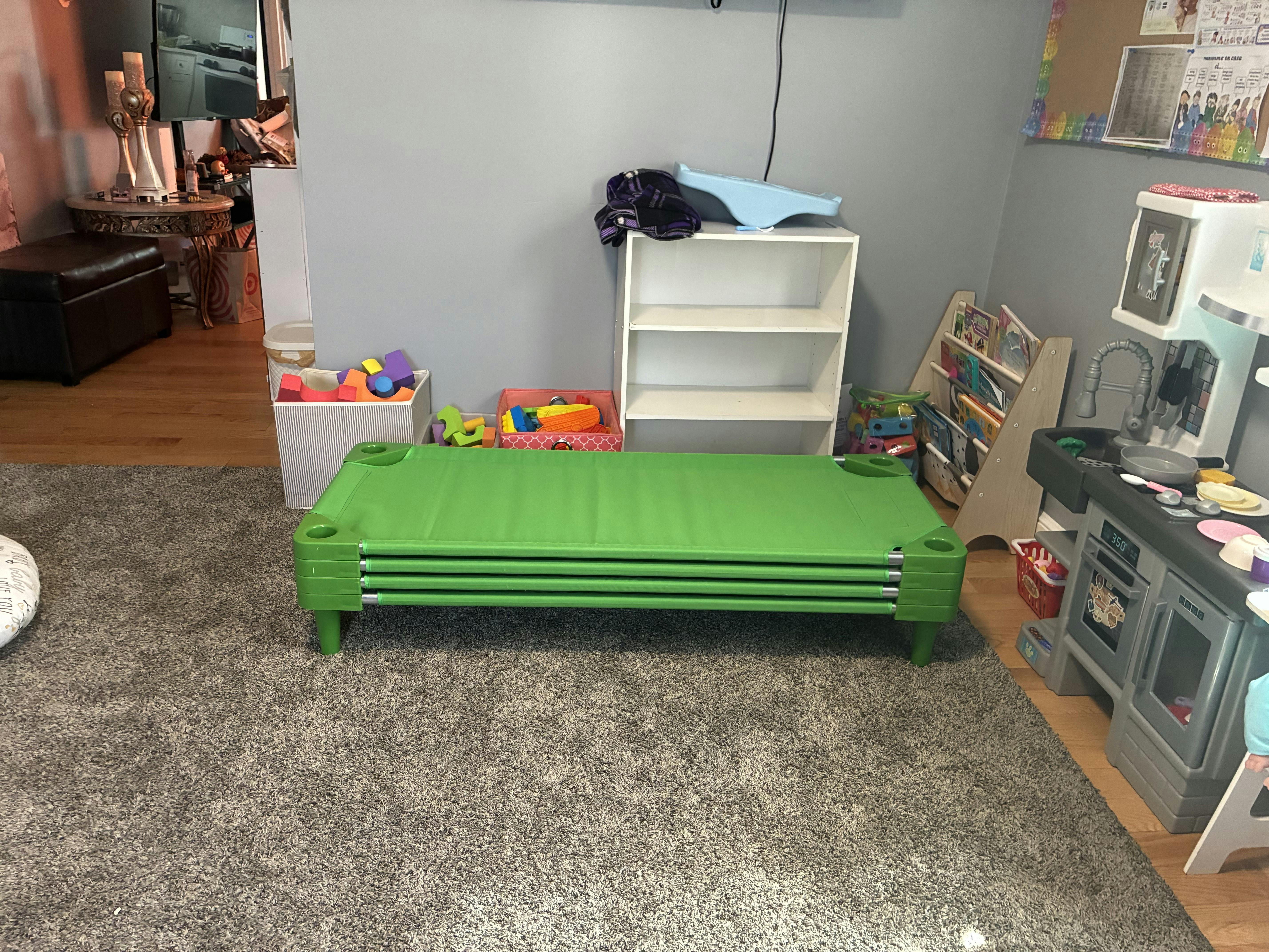 Stacked green plastic sleeping cots in a play area