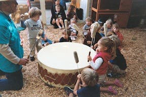 Adult and children playing a large drum