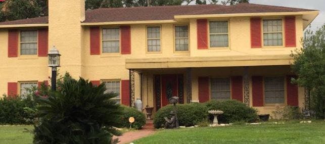 Two-story house with yellow siding and red shutters