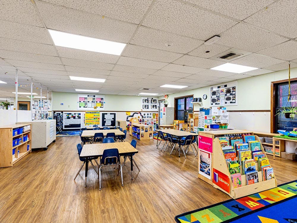 Empty colorful children's classroom with tables, chairs, and shelves