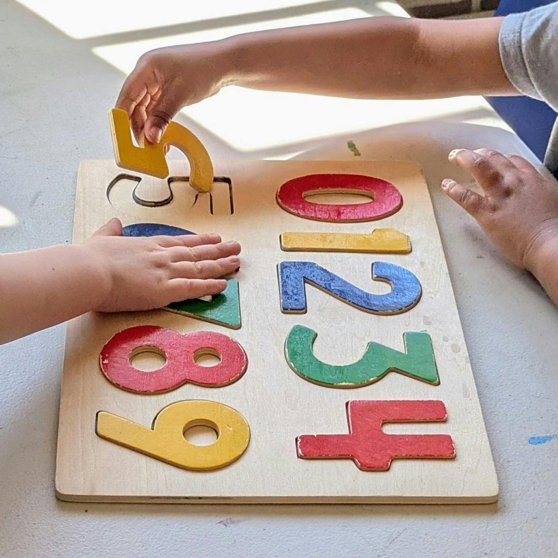 People using a wooden number puzzle on a table