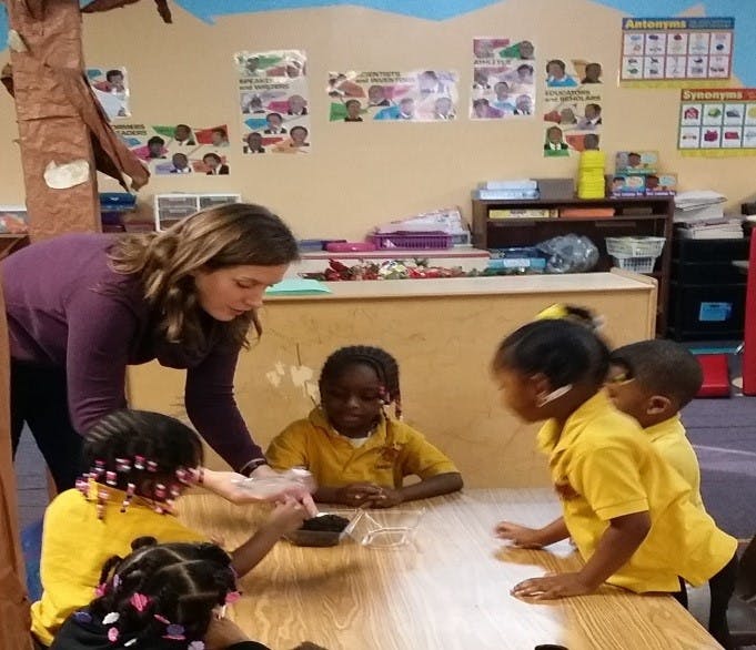 Person helping children at a table in a classroom