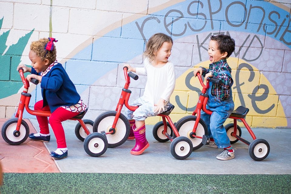 Three children on red tricycles