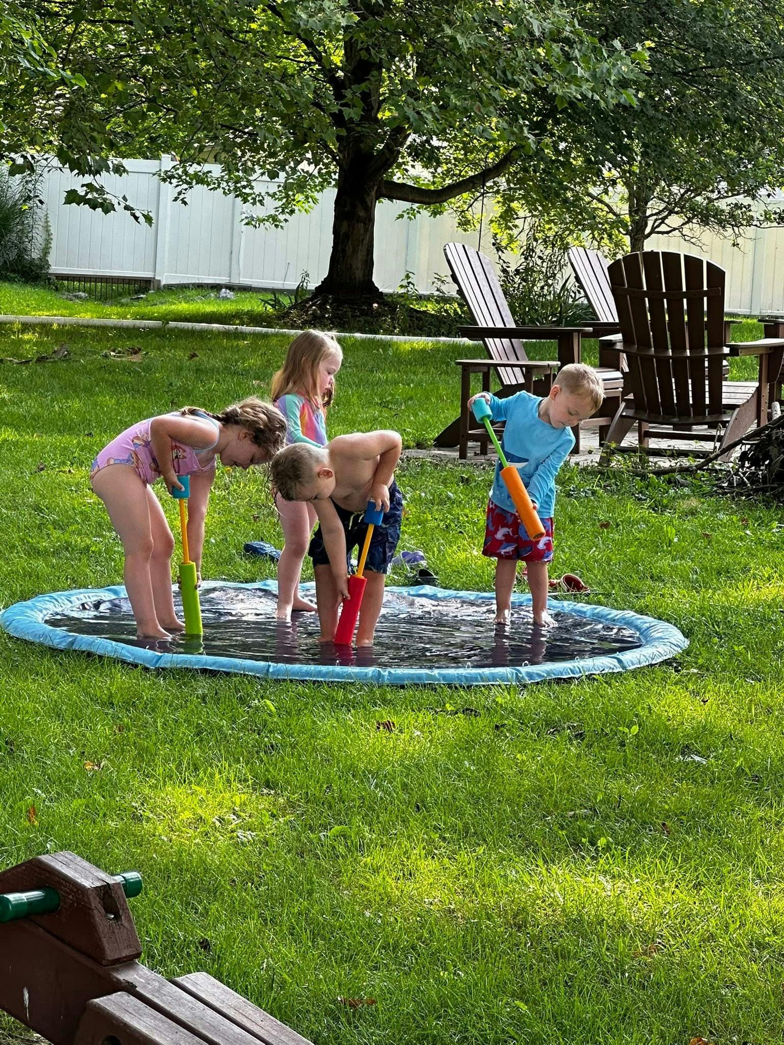 Children playing in a small inflatable pool with water toys