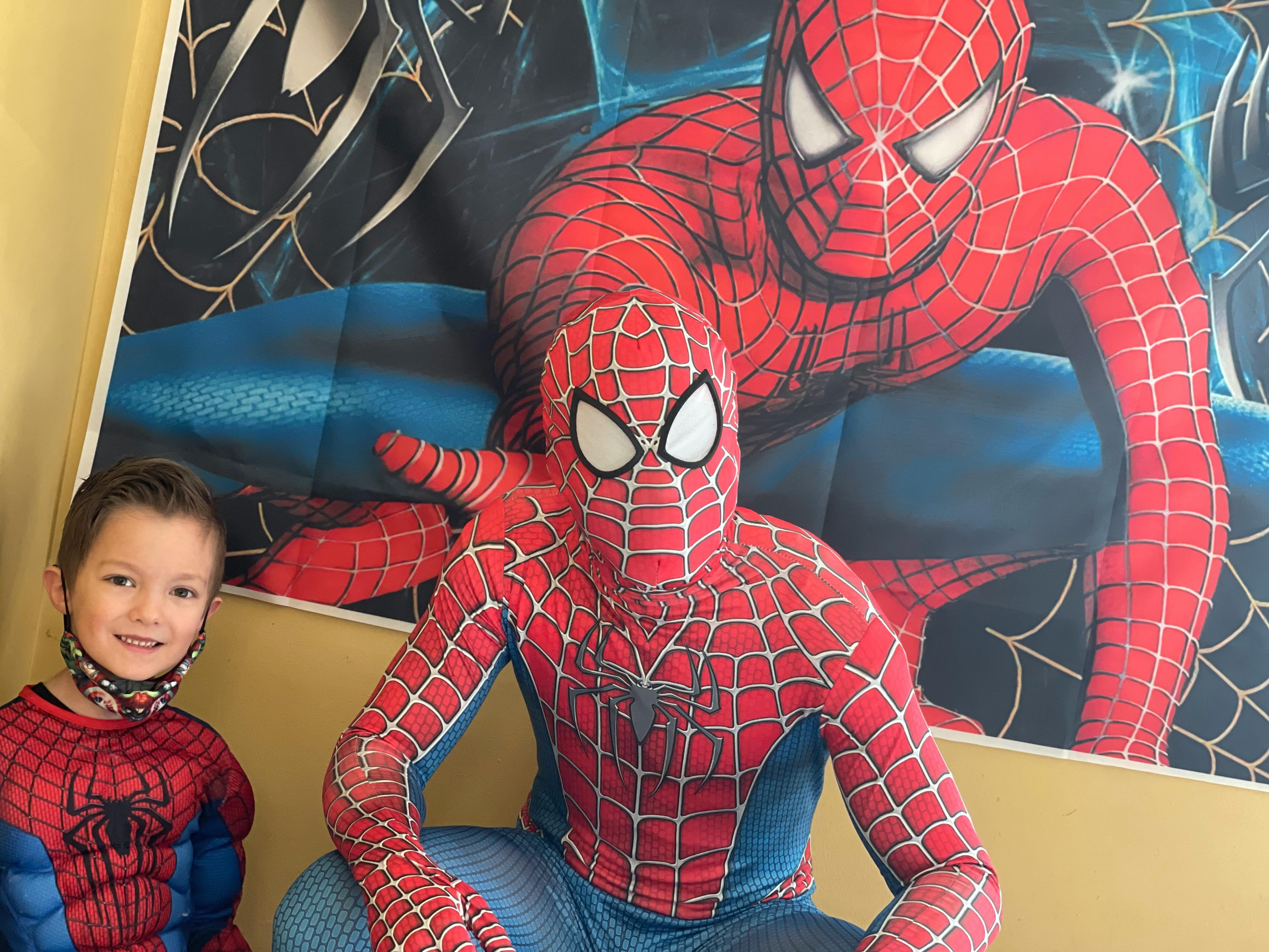 Child in Spider-Man costume next to person in Spider-Man costume