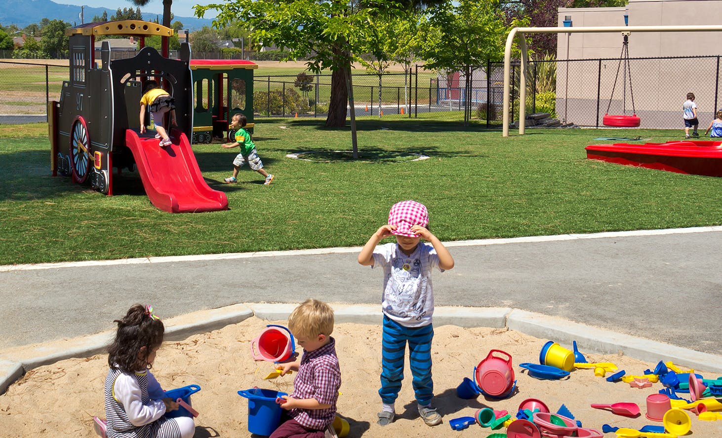 Children playing in a sandbox and on playground equipment
