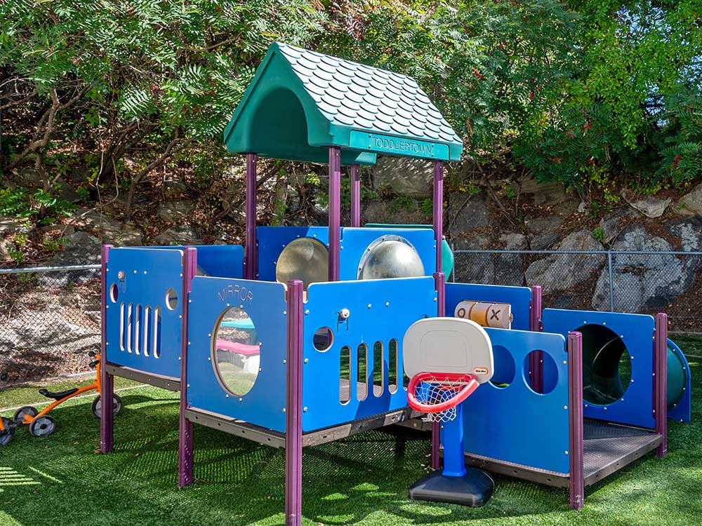 A toddler playground structure with slides, tunnels, and a basketball hoop
