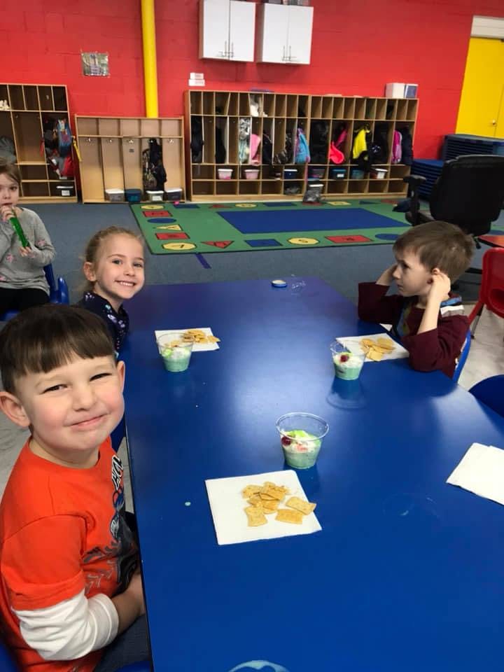 Children sitting at a table with snacks in a classroom