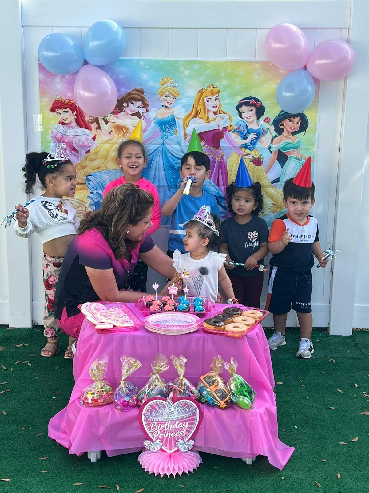 Adult and children celebrating a birthday with a table of treats