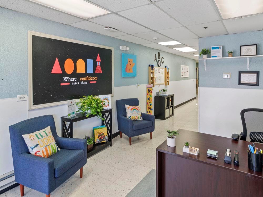 Lobby area of a learning center with a reception desk, chairs, and blackboard