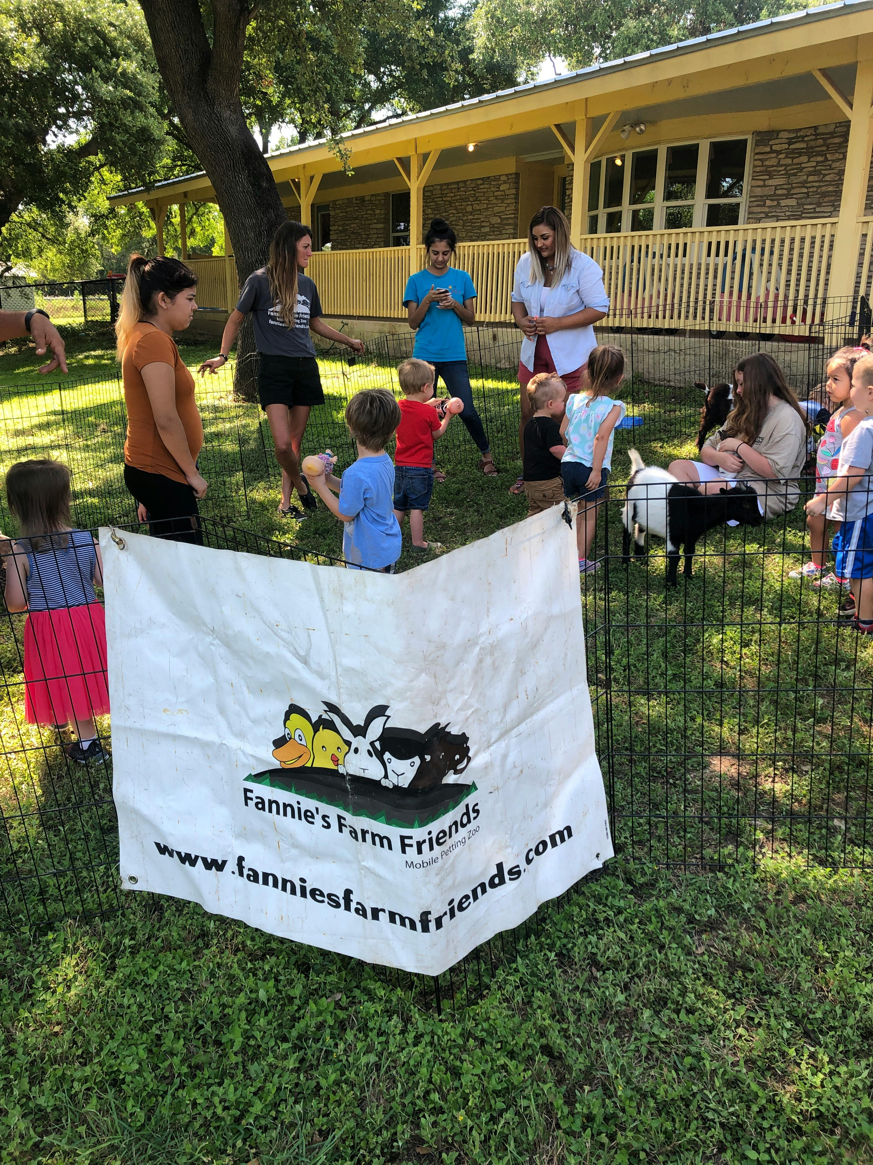 Adults and children interacting with goats in an outdoor setting