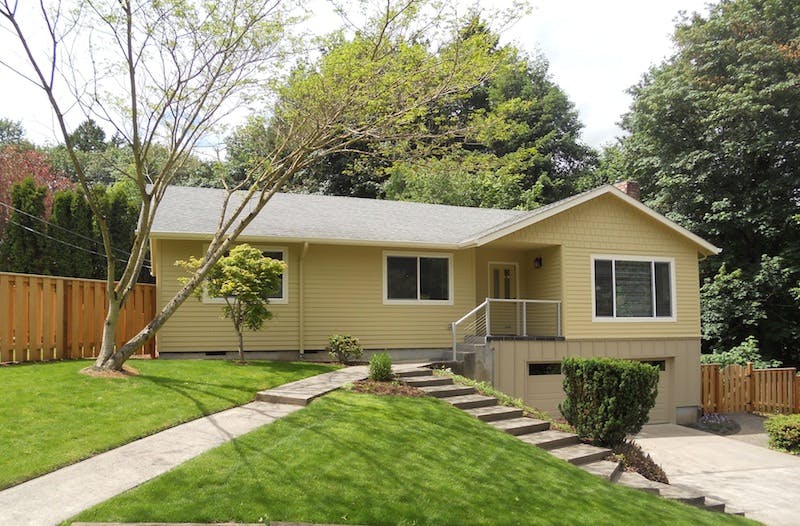 Single-story house with a light yellow exterior and a gray roof