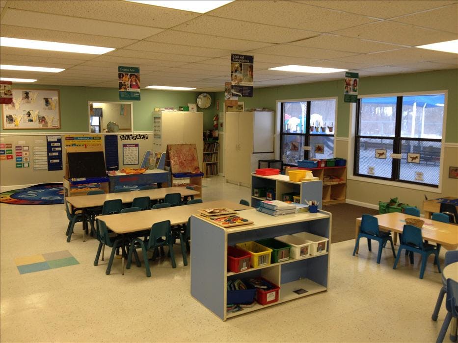 Classroom with small tables and chairs, shelves, and large windows