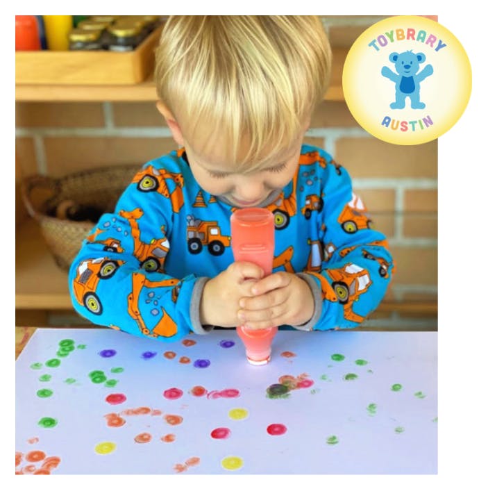 Child squeezing paint onto paper