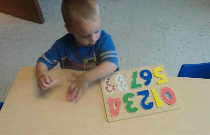 Child playing with a number puzzle on a table