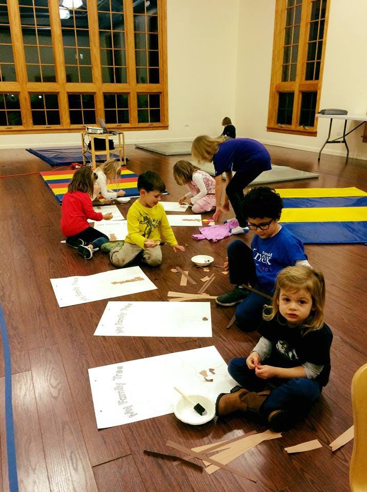 Children and adults sitting on the floor doing crafts