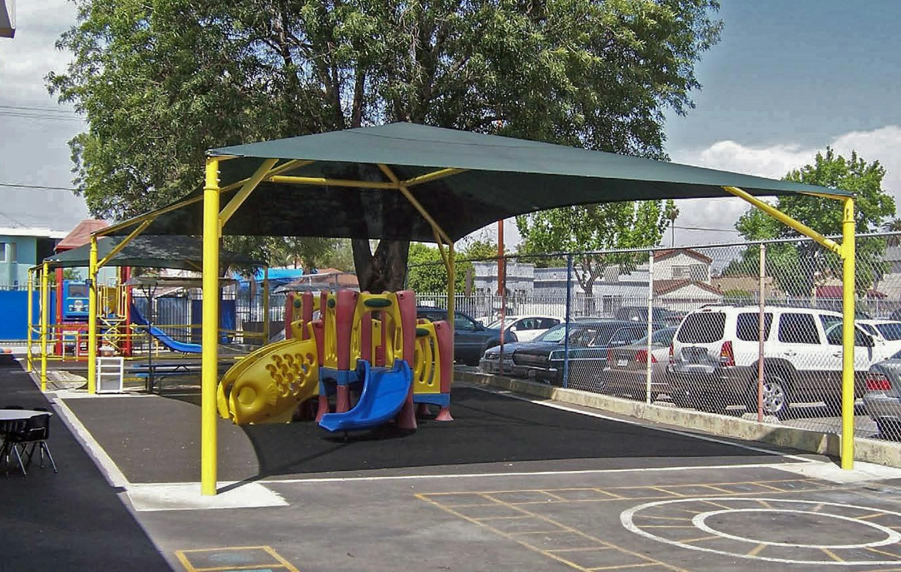 Playground with slides and climbing structures under a large shade canopy