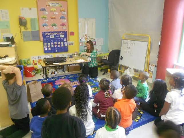 Adult teaching a group of children in a classroom