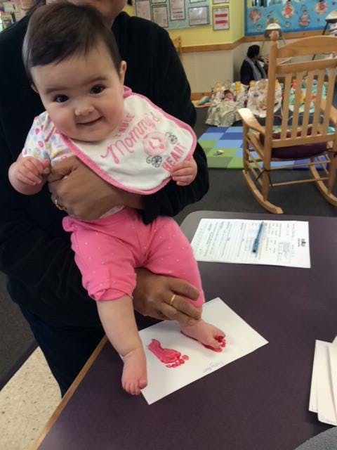 Person holding a child making a footprint on paper