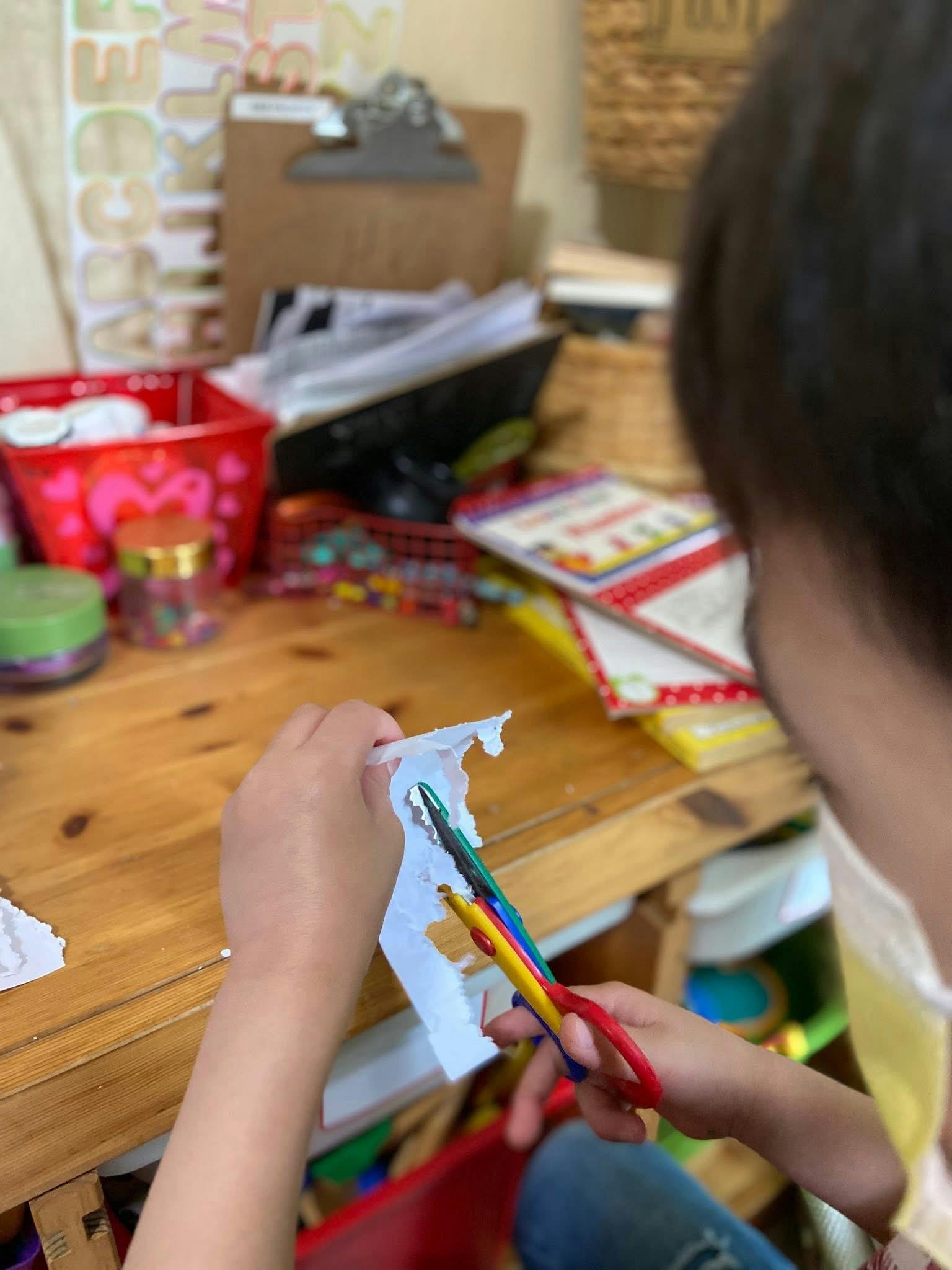 Child cutting paper with scissors at a table
