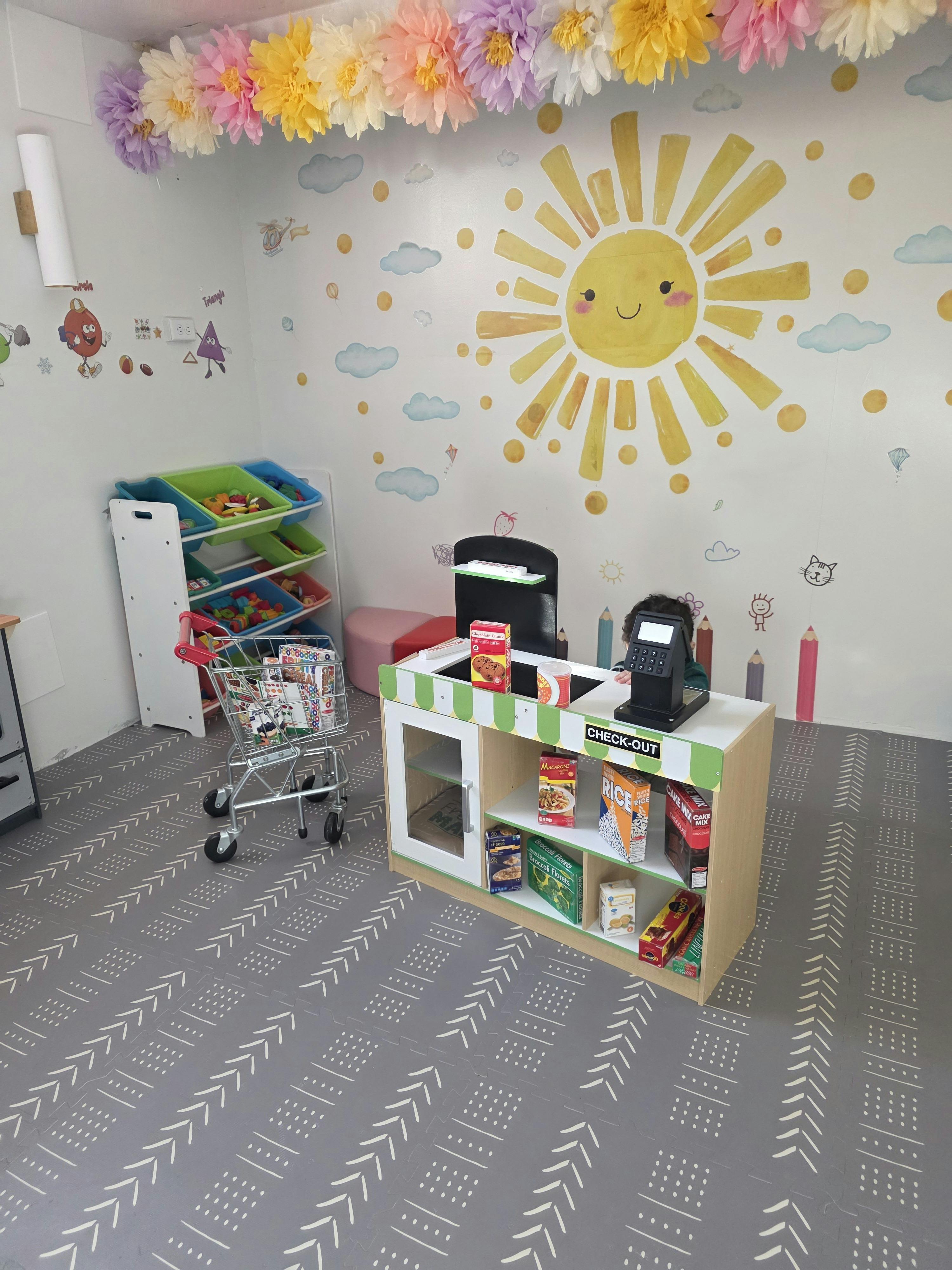 Child playing with a toy checkout counter and shopping cart