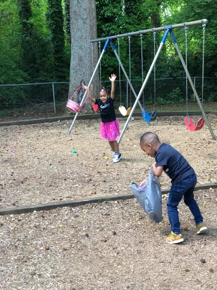 Two children playing on a playground with a swing set