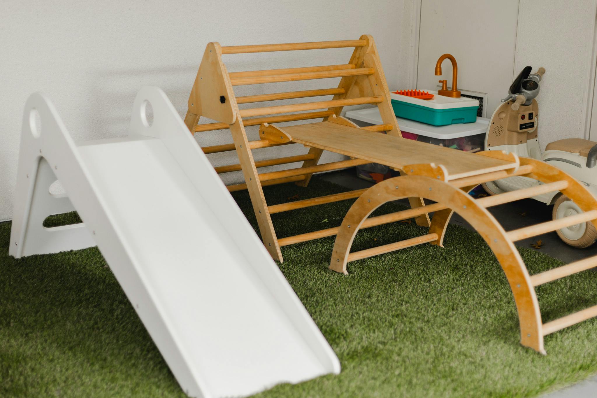White slide and wooden climbing structure on green turf