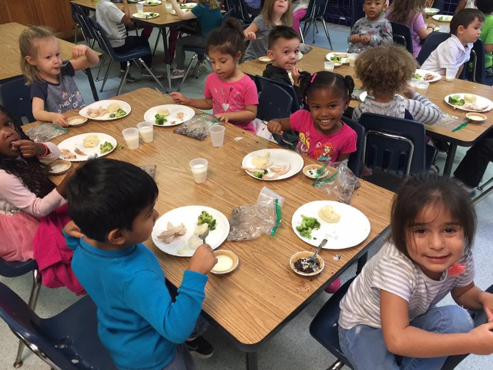Children eating meals at tables in a classroom
