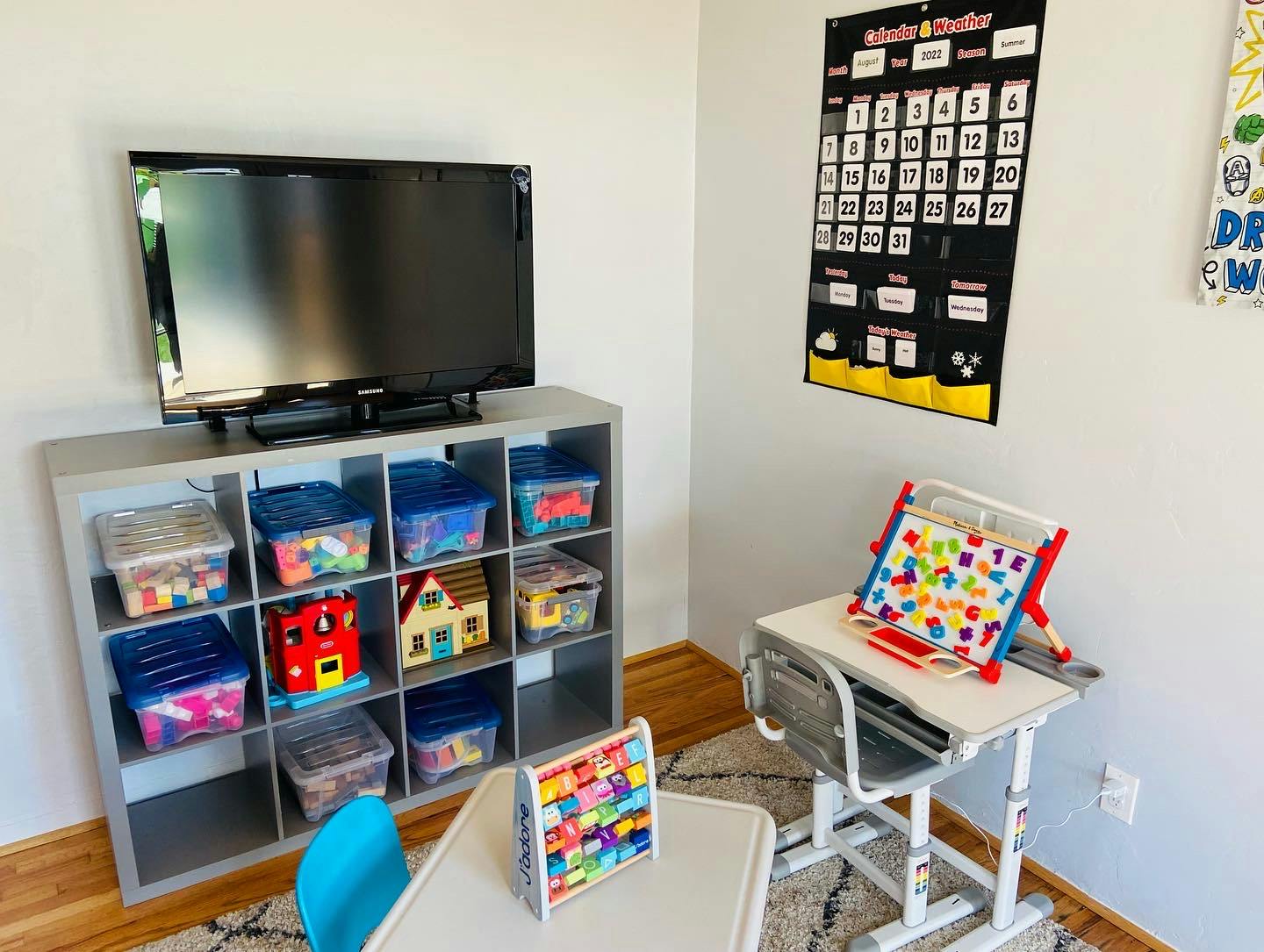 TV on a shelf with toy bins, child's desk, and calendar