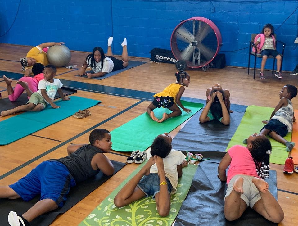Children and adults doing yoga on mats in a gym