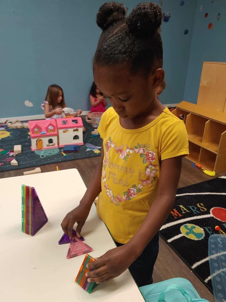 Child playing with magnetic tiles at a table in a classroom