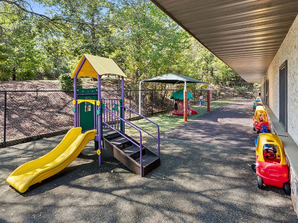 Children's playground with yellow slide, play structure, and small riding toys