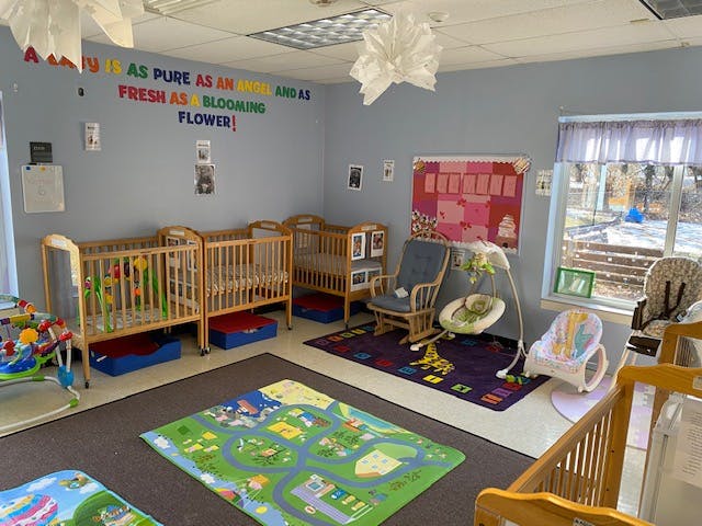 Nursery room with multiple cribs, a rocking chair, and play mats