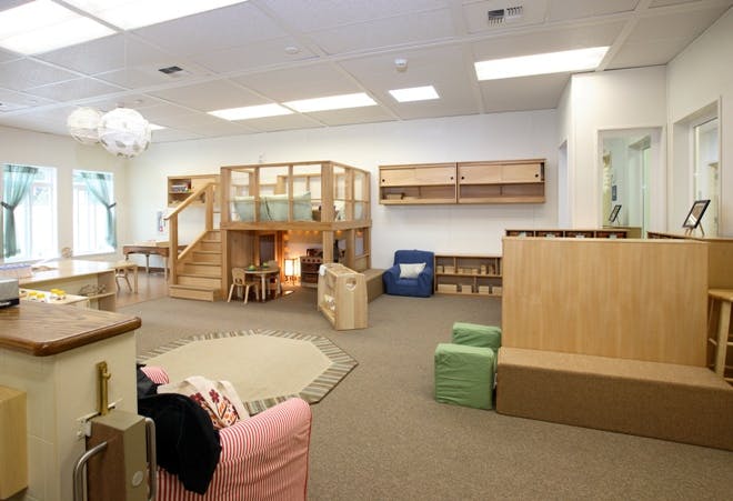 Indoor play area with wooden structures, seating, and a rug