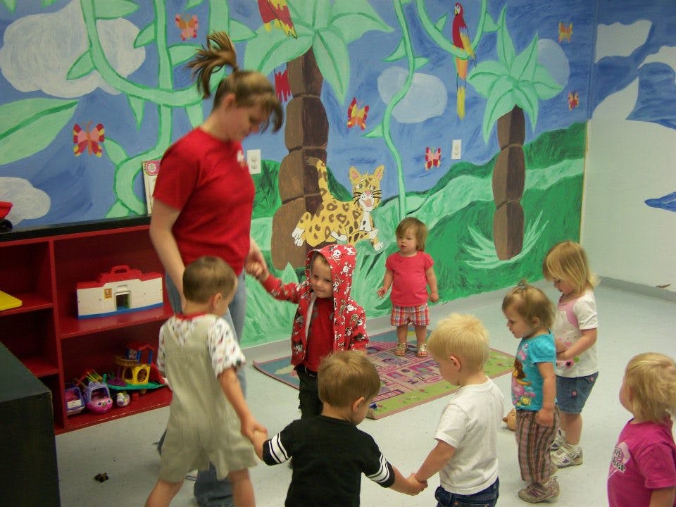 Adult and multiple children standing in a room with a painted mural