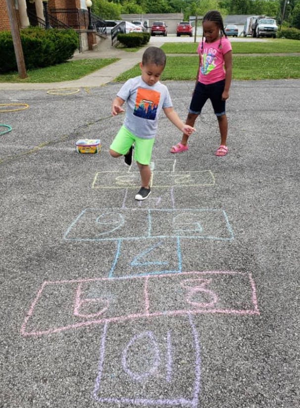 Child playing hopscotch while another child watches