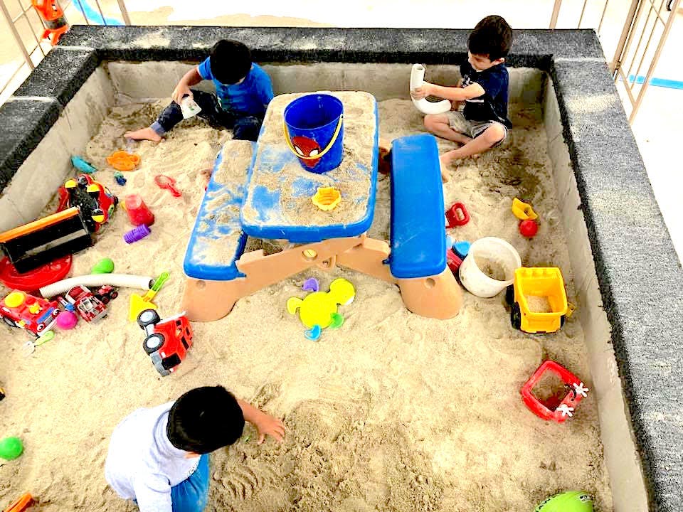 Children playing in a sandbox with toys and toys