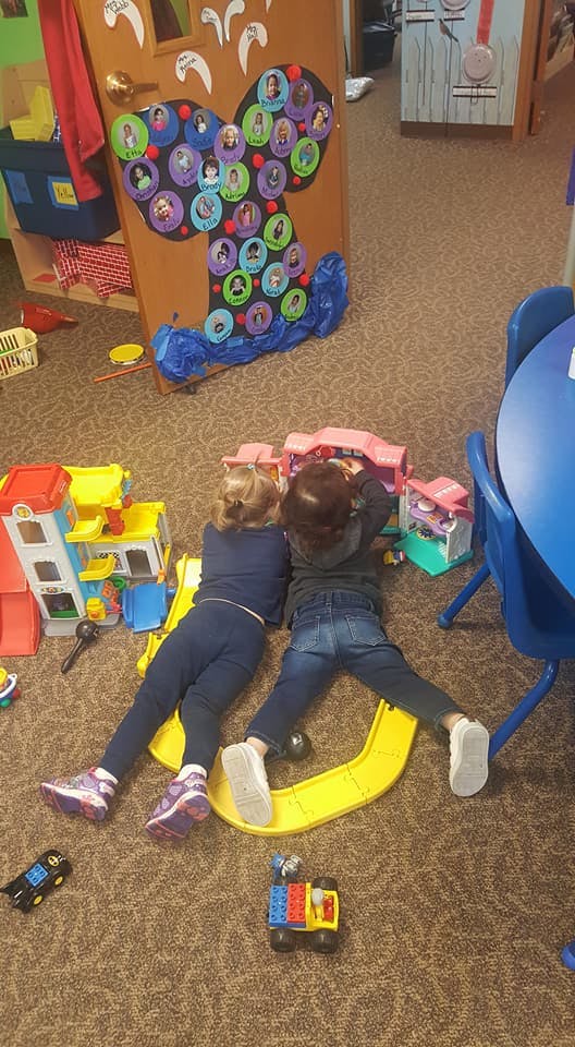 Two children lying on the floor playing with toys