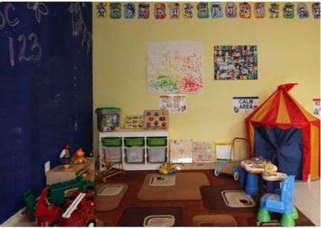 Playroom with a blue chalkboard, toy storage, and a red and yellow tent