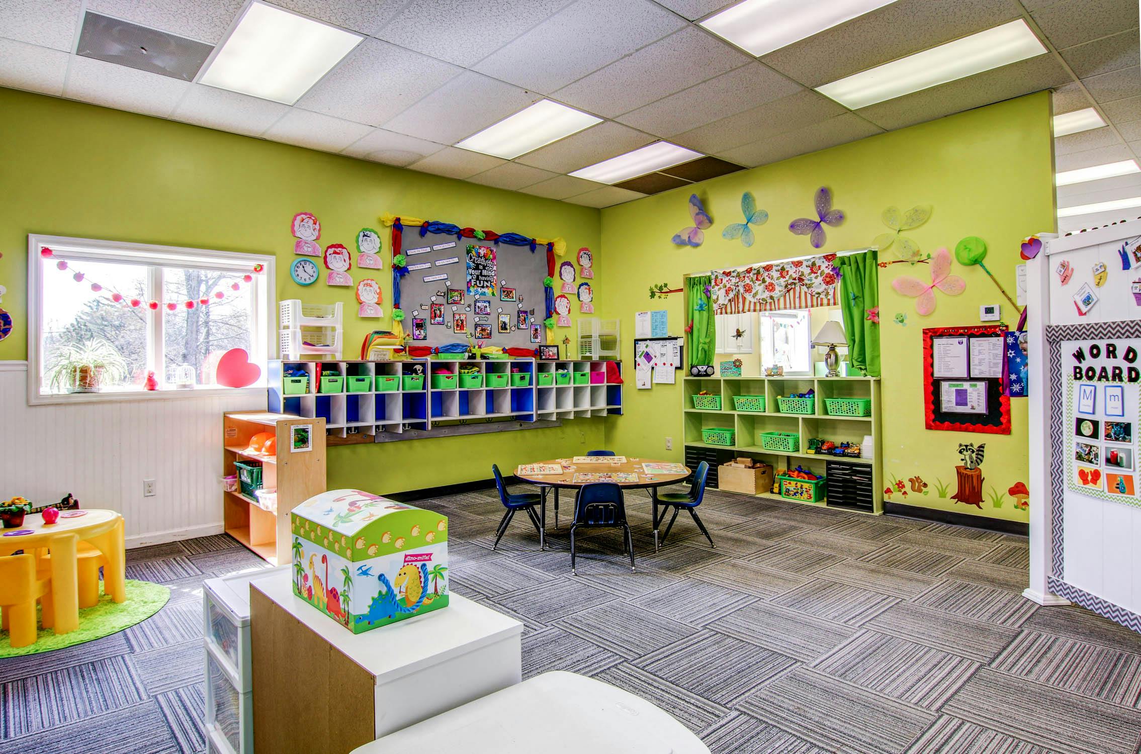 Classroom with green walls, small tables, and storage cubbies