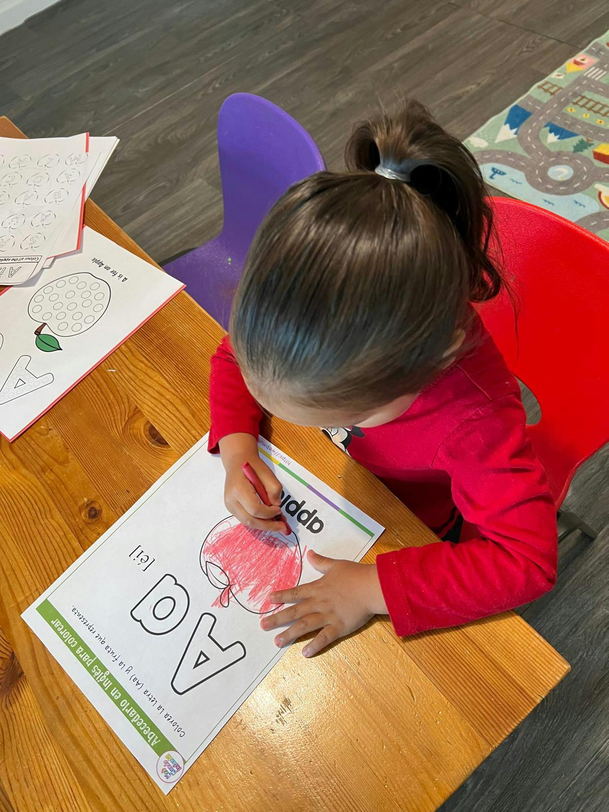 Child coloring an apple on a worksheet